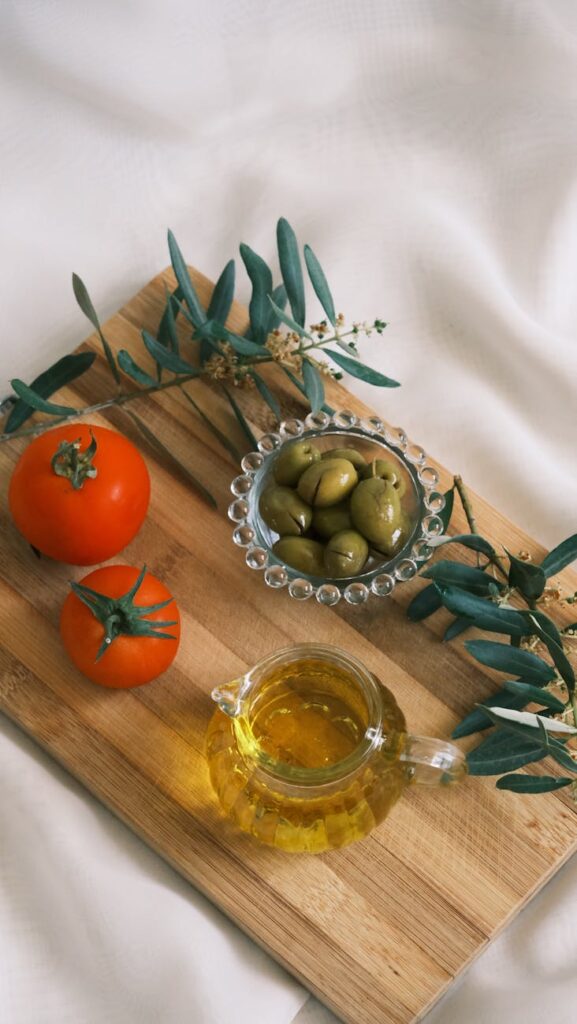 olives tomatoes and olive oil in a glass standing on a cutting board