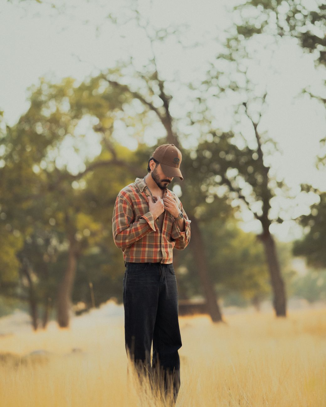man in plaid shirt standing in sunlit field