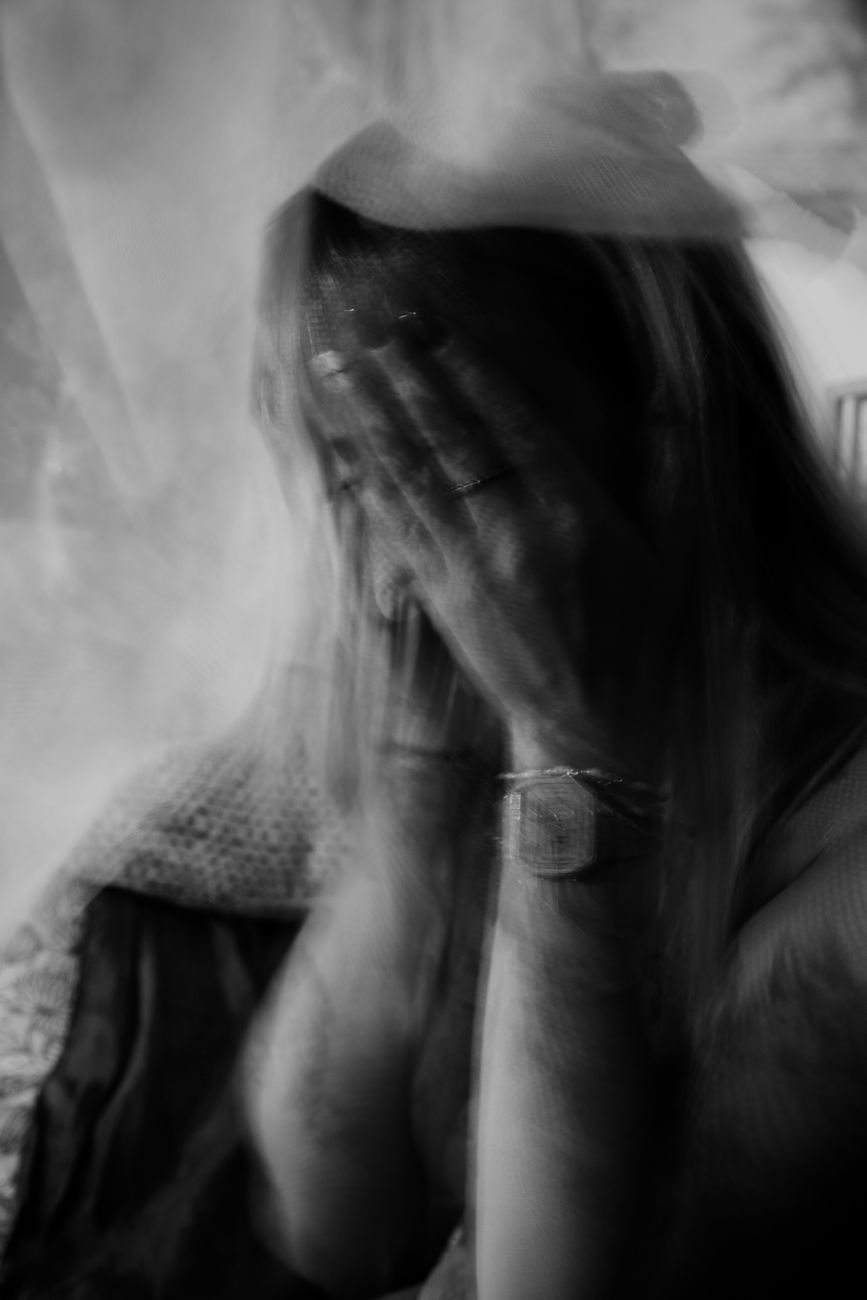 grayscale photo of woman covering face with her hands